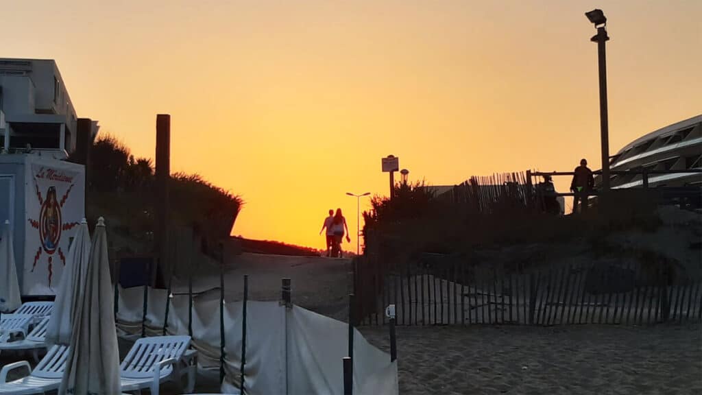 Couple walking into Cap d’Agde naturist beach at sunset